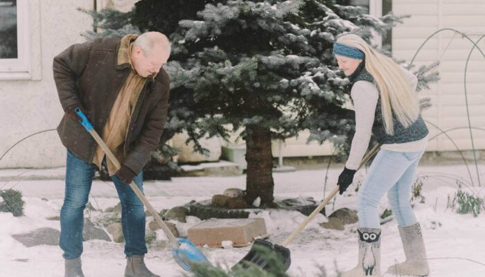 muškarac i žena čiste sneg lopatama